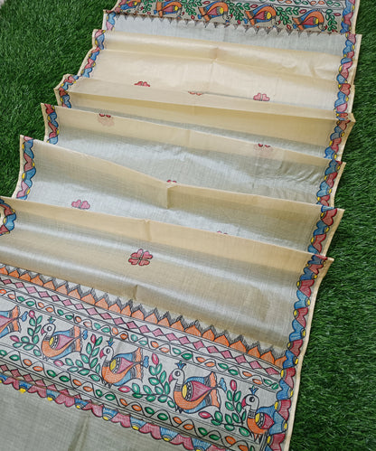 Natural beige Madhubani Tussar silk stole showcasing colorful hand painted borders of peacocks, fish, and temple geometric mithila patterns